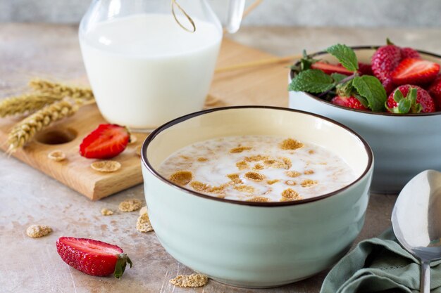 Healthy breakfast  whole grain flakes milk and fresh strawberries on stone or slate background