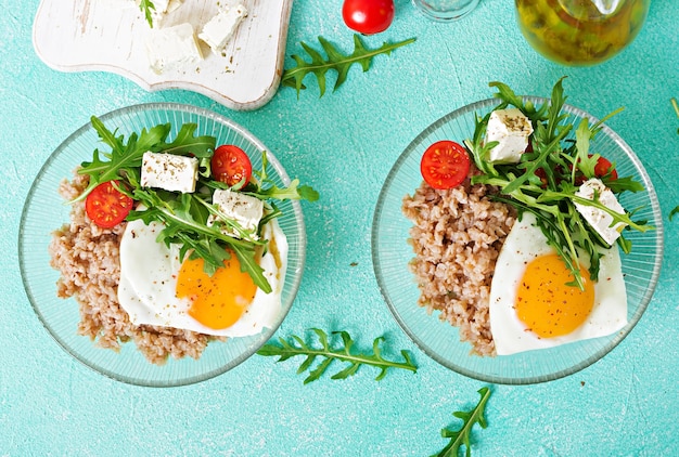 Healthy breakfast with egg, feta cheese, arugula, tomatoes  and buckwheat porridge 