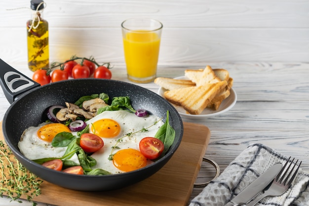 Healthy breakfast with fried eggs, tomatoes, mushrooms and spinach leaves