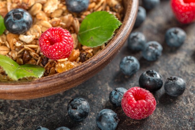 Healthy breakfast with granola and berries on dark background.