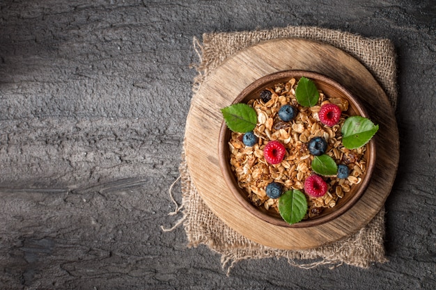 Healthy breakfast with granola and berries on dark background