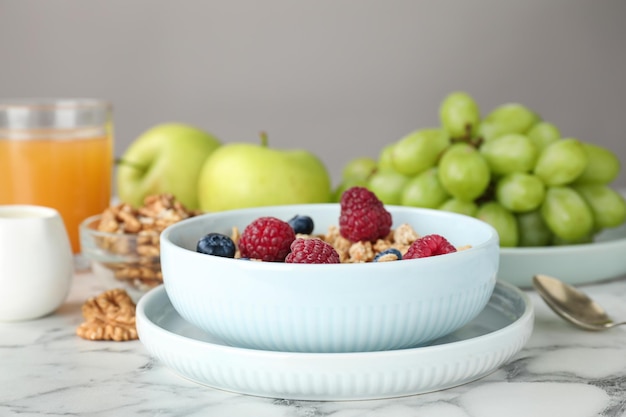 Healthy breakfast with granola and berries served on white marble table