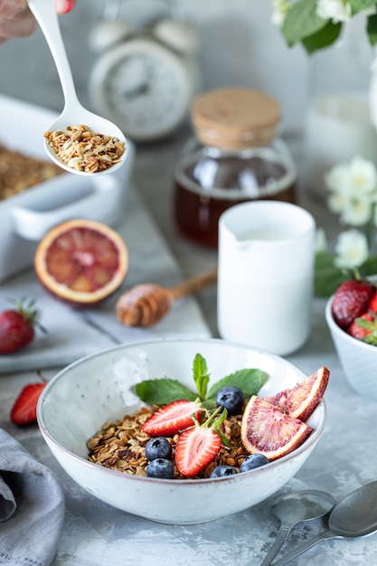 Sana colazione con muesli, yogurt, frutta, bacche su un piatto bianco