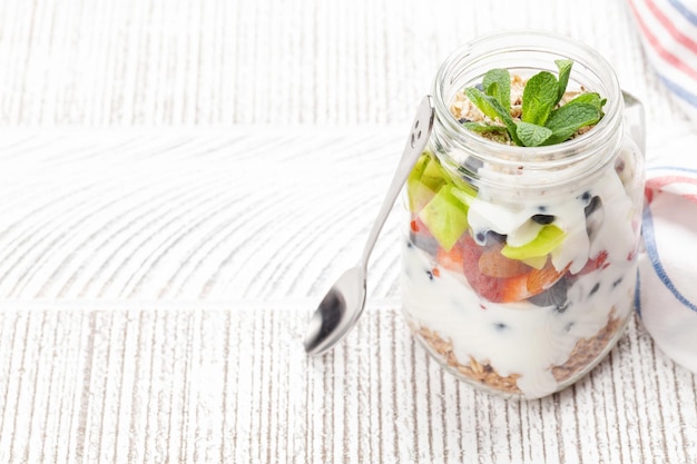 Здоровый завтрак с баночкой йогурта мюсли и свежими ягодами