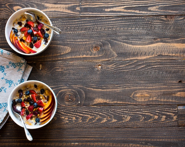 Foto sana colazione con latte, muesli e frutta, su uno sfondo di legno.