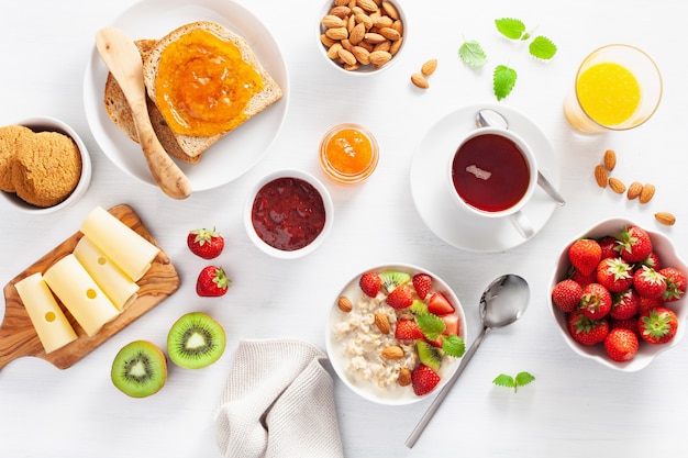 Healthy breakfast with oatmeal porridge, strawberry, nuts, toast, jam and tea. Top view