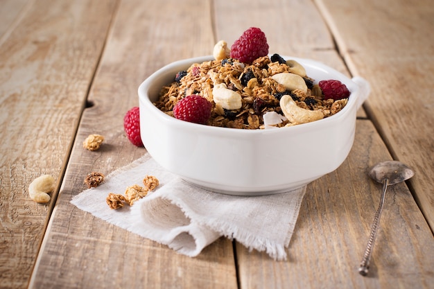 Prima colazione sana con granola di avena, lampone e noci sul tavolo in legno