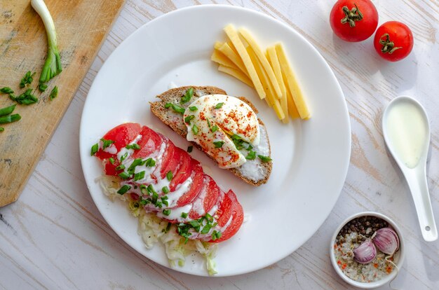 Prima colazione sana con uovo in camicia, pane integrale, pomodori e formaggio