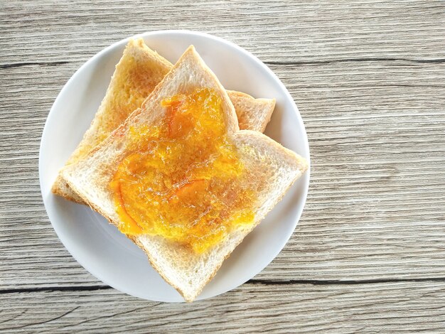 Foto sana colazione con gustosi toast per la colazione (con marmellata di arance e ananas) sul tavolo di legno.