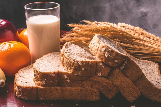 Здоровый завтрак с хлебом из цельной пшеницы, молоком и фруктами на столе