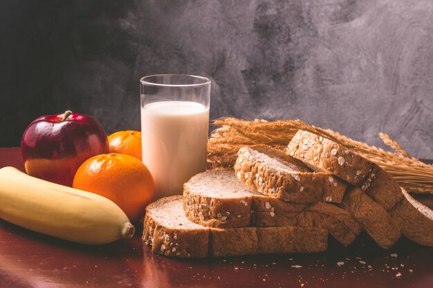Здоровый завтрак с хлебом из цельной пшеницы, молоком и фруктами на столе