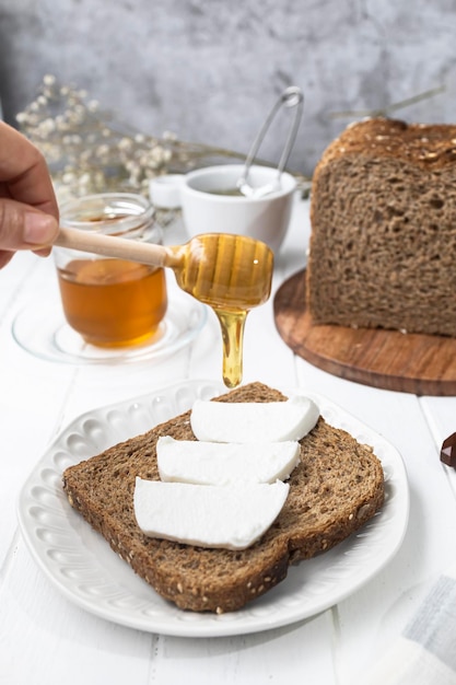 Healthy breakfast with wholemeal bread fresh goat cheese and raw honey A delicious breakfast