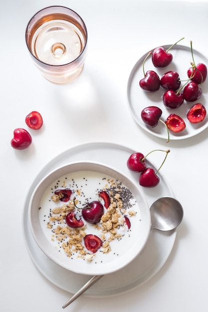 Healthy breakfast. Yogurt, chia seeds, granola and cherries in a white bowl