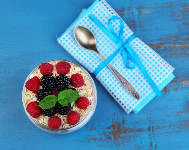 Healthy breakfast yogurt with fresh fruit berries and muesli served in glass jar on color wooden background