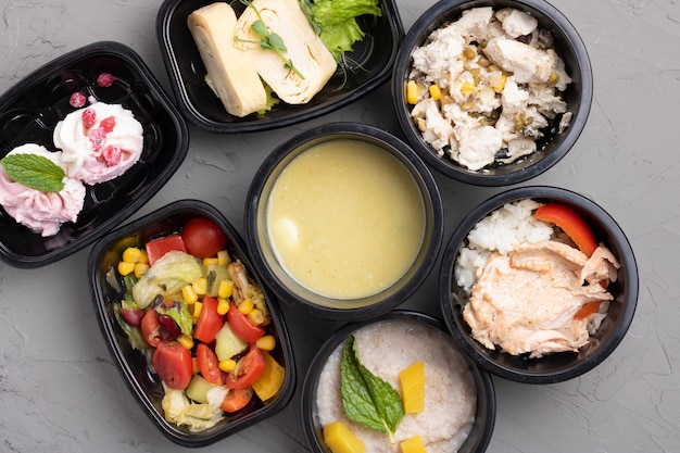 Healthy business lunch boxes grey table. Vegetables and fried chicken lunch box on working desk, top view