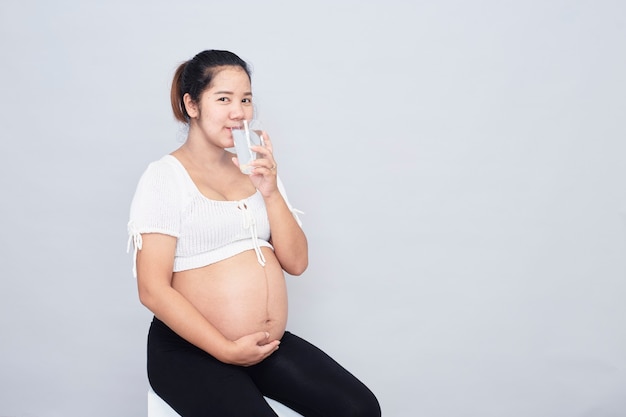 健康的なカルシウム飲料。健康的なカルシウム飲料に座っている妊娠中の若いアジアの女性。妊娠中の若いアジアの女性が牛乳のガラスを持って座っている