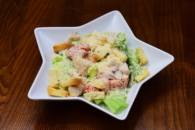 Healthy chicken caesar salad with parmesan cheese. Gren salad in bowl on wooden table. Healthy food style