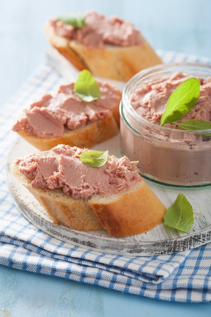 Healthy chicken liver pate with sage in jar and on bread