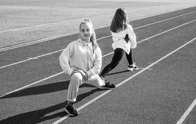 Ragazze in buona salute dei bambini che allenano il fitness sullo sport della pista da corsa dello stadio