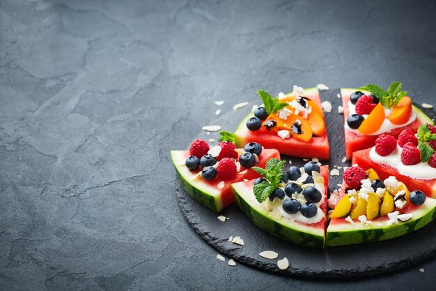 Healthy clean eating dieting and nutrition seasonal summer concept Watermelon pizza with berries fruits yogurt feta cheese on a table Copy space background