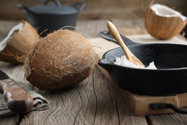 Healthy coconut oil for cooking on frying pan Coconuts on wooden kitchen table