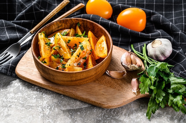 Healthy and colorful salad with yellow tomatoes and parsley. Gray background. Top view