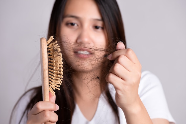 Concetto sano. la donna mostra la sua spazzola con i capelli danneggiati a perdita lunga