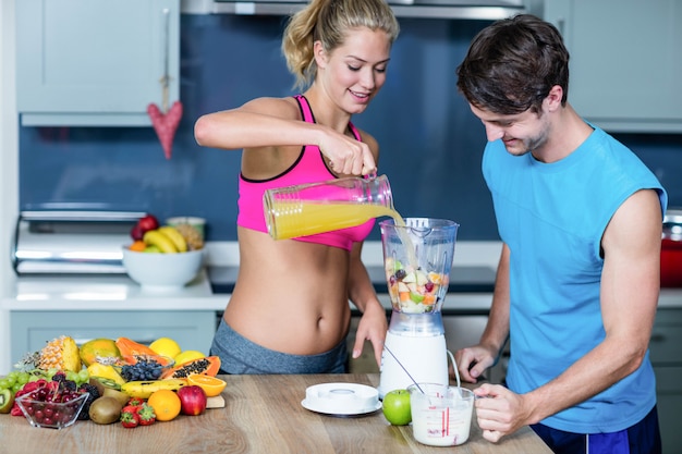 Healthy couple preparing a smoothie in the kitchen