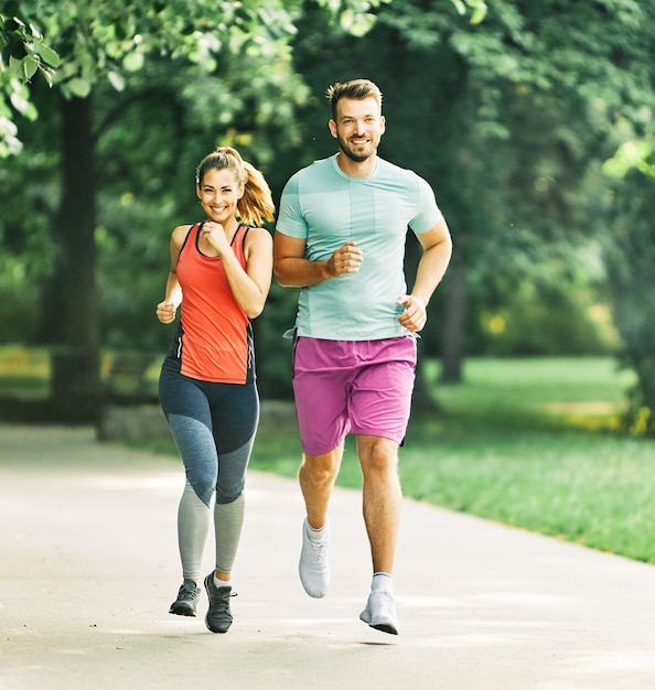 Healthy couple running in the park in morning doing excercise enjoying healthy fit life