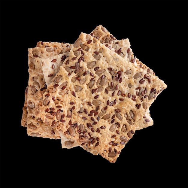 Healthy crackers with sunflower seeds and linseed seeds isloated on black Top view closeup