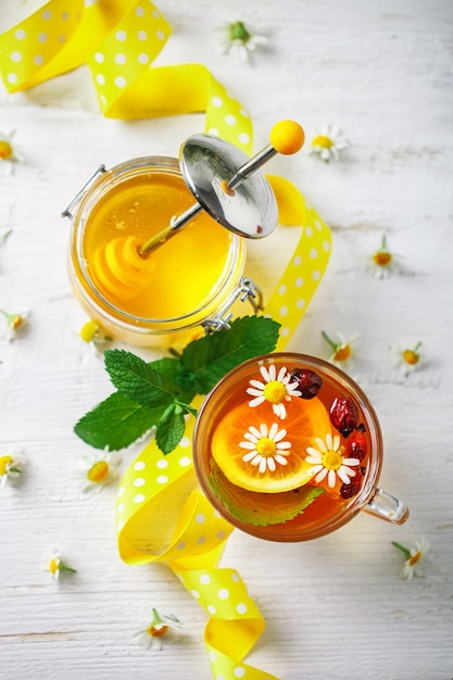 A healthy Cup of tea, a jar of honey and flowers. 