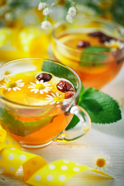 A healthy Cup of tea with lemon, rosehip, mint and flowers. Selective focus.