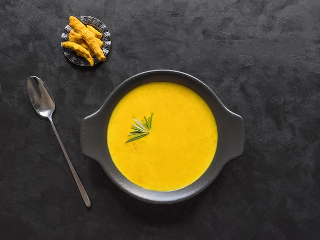 Healthy curcuma cream soup on black wall