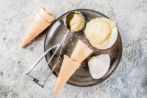 Foto dessert sano, gelato vegan biologico al cocco servito a metà di cocco e coni gelato