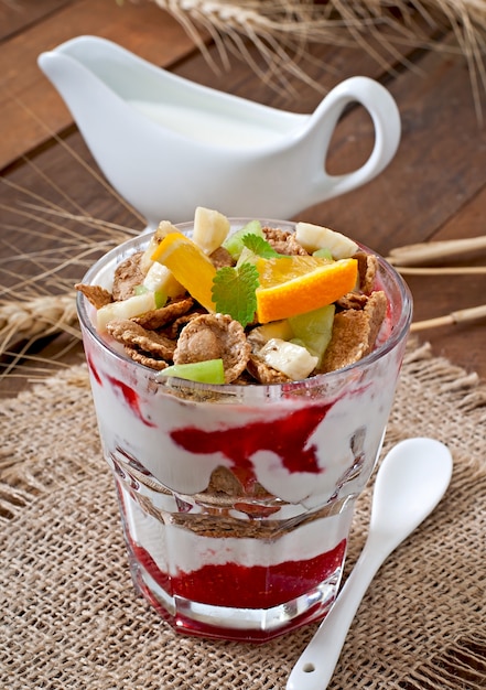 Healthy dessert with muesli and fruit in a glass bowl on the table