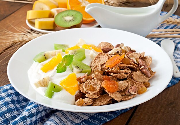 Healthy dessert with muesli and fruit in a white plate on the table