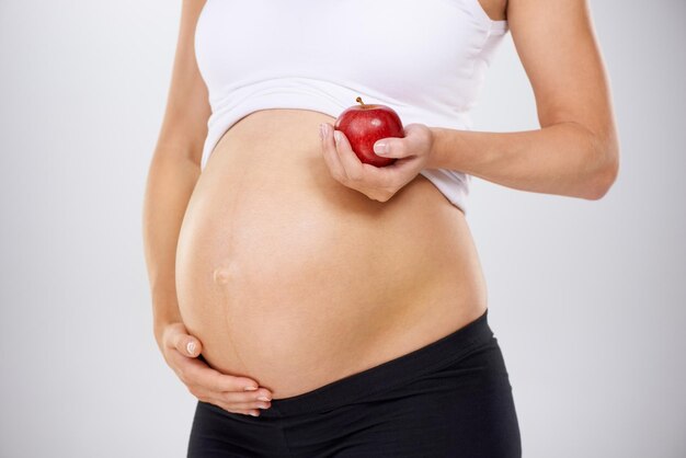 Healthy diet for the baby Cropped image of a pregnant woman holding an apple and touching her stomach lovingly