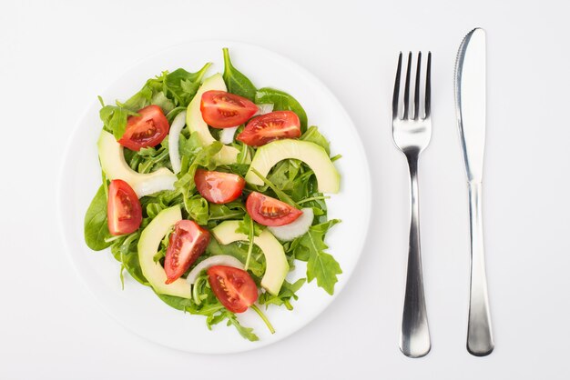 건강한 다이어트 개념입니다. 흰색 배경에 격리된 올리브 오일 포크와 나이프가 있는 샐러드 접시의 오버헤드 클로즈업 보기 사진 위