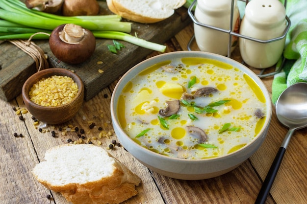 Concetto di alimentazione sana e dietetica zuppa di funghi con bulgur e crema su tavola rustica