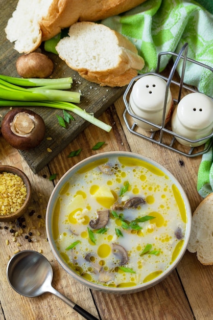 Healthy and diet eating concept Mushroom cream soup with bulgur and cream on rustic table