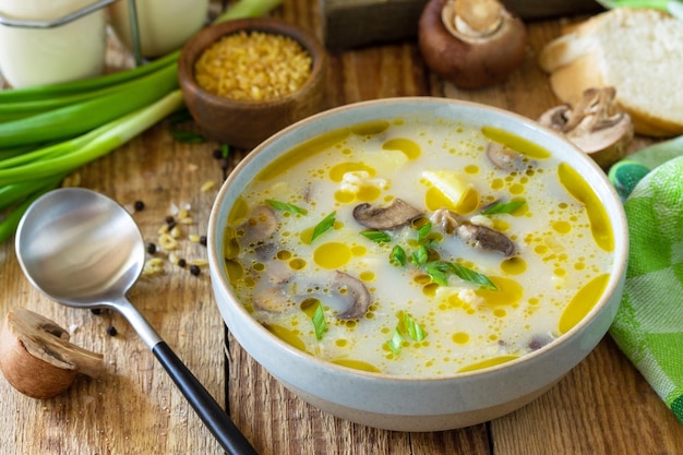 Healthy and diet eating concept Mushroom cream soup with bulgur and cream on rustic table