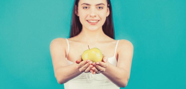 健康的なダイエット食品アップル ブルーの背景を保持している完璧な笑顔を持つ女性