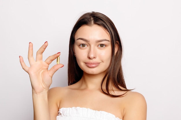 Healthy Diet Nutrition. Beautiful Smiling Young Woman Holding Fish Oil Pill In Hand