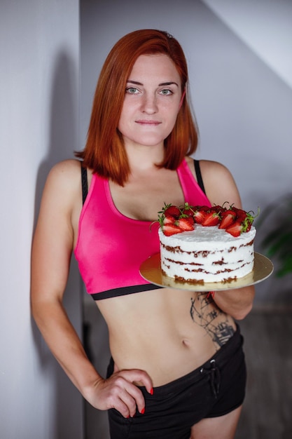 건강한 식단과 영양 집에서 천연 케이크를 먹고 카메라를 보고 있는 행복한 아름다운 젊은 여성의 초상화입니다.