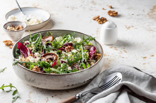 Healthy diet salad with feta cheese arugula mushrooms walnut in ceramic bowl