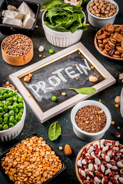 Healthy diet vegan food, veggie protein sources: Tofu, vegan milk, beans, lentils, nuts, soy milk, spinach and seeds. Top view on white table.