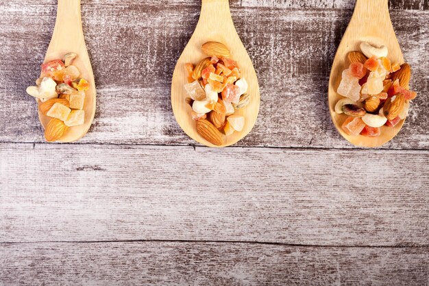 Healthy different type of nuts and sweet in wooden spoon on wooden background in studio photo