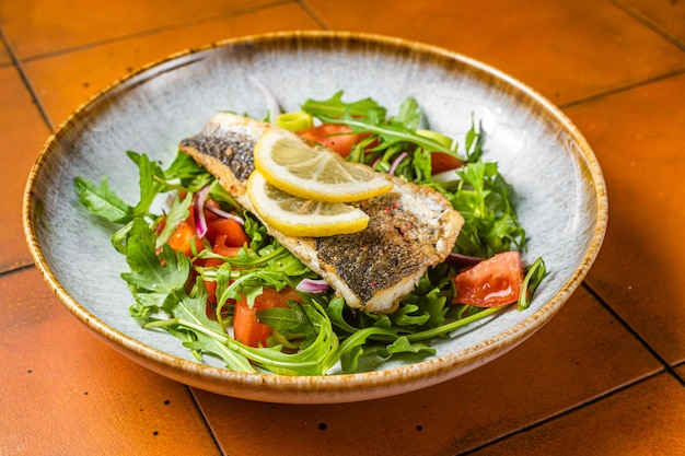 Healthy diner with sea bass fillet and vegetable salad seabass fish Orange background Top view