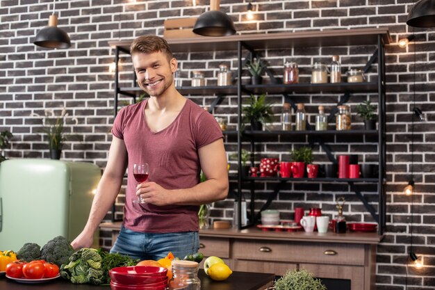 Cena salutare. un bell'uomo dai capelli biondi che indossa jeans e maglietta che cucina una cena sana per una moglie adorabile