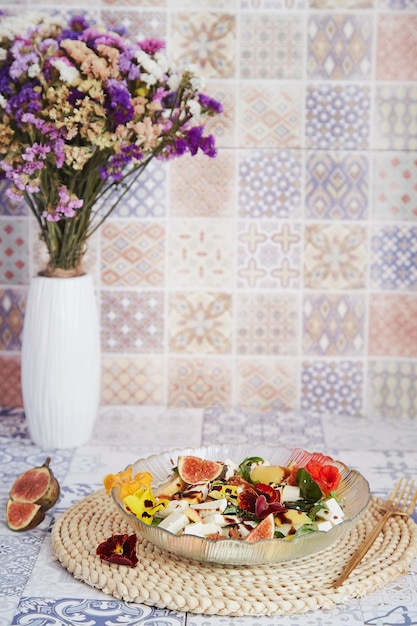 Healthy dinner salad with feta edible flowers figs peach basil on ceramic tile background with sunflowers